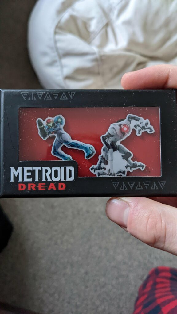 Metroid dread pins arrived, the chozo text on the box is perplexing, the top left says metroid, the bottom right reads nabular, yes nAbular NOT nEbular, its an odd choice to put there.