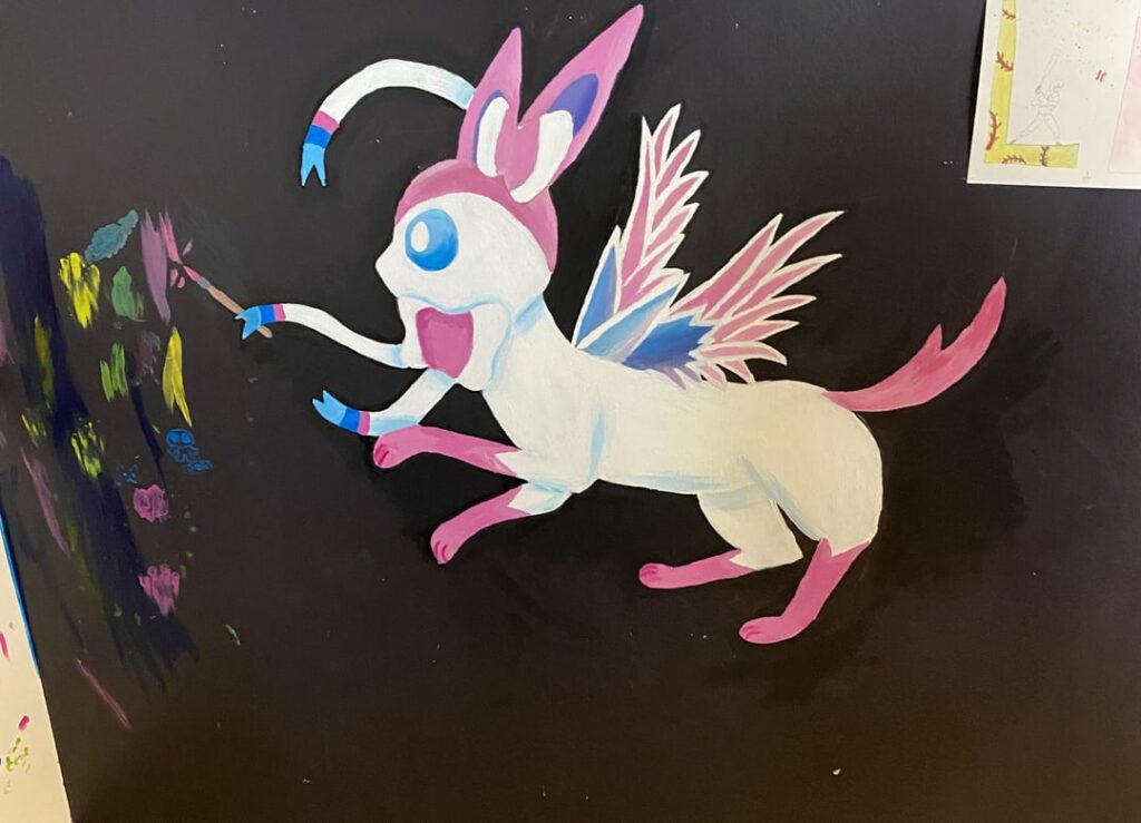 The Sylveon I painted on my art room walls compared to the one I got today [OC]