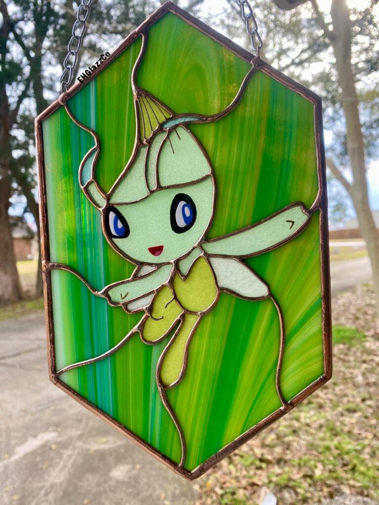 I’m a stained glass artist and this is my stained glass Celebi! Swipe to see her glow in the dark! This was 100% made, by me. Hand painted by me as well.