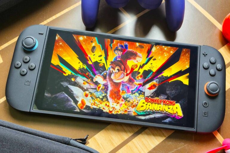 Switch 2 with Donkey Kong Bananza art on screen on wood pattern table next to accessories.