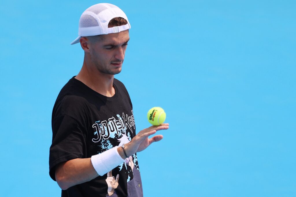 male tennis player looking at a tennis ball in his hand