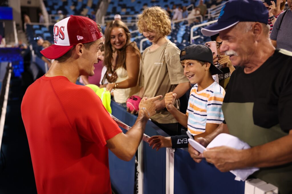 ATP player talking to a smile child and fans on the sidelines